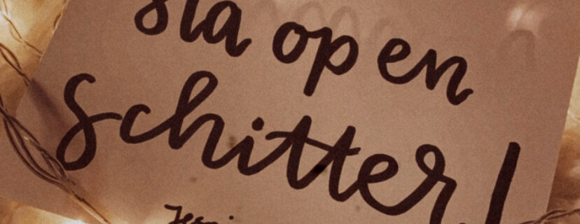 Kaartje met de inspirerende tekst 'Sta op en schitter!' omringd door warme sfeerverlichting op een zachte ondergrond.