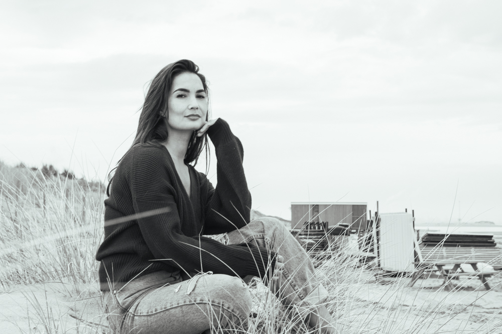 Zwart-wit portret van een vrouw op het strand tijdens een ontspannen fotoshoot in Nederland.