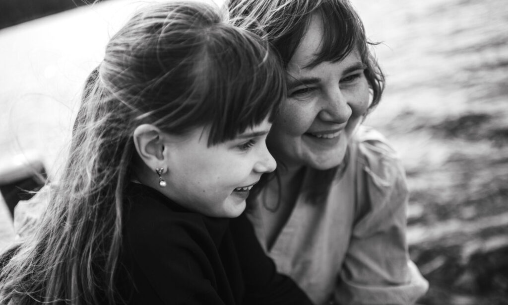 Zwart-wit foto van moeder en dochter tijdens een intiem moment bij een gezinsfotoshoot.
