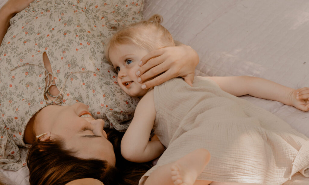 Moeder en dochter liggend op een kleedje tijdens een motherhoodshoot