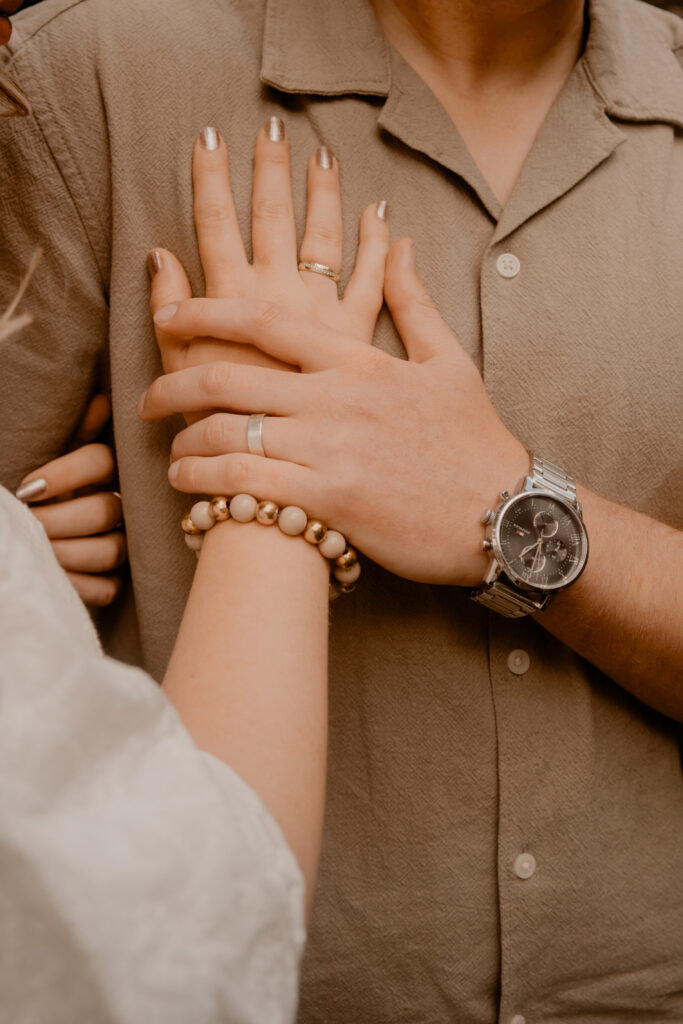 Detailfoto van stijl; er is een vrouwelijke hand met sieraden en een mannelijke hand met horloge te zien